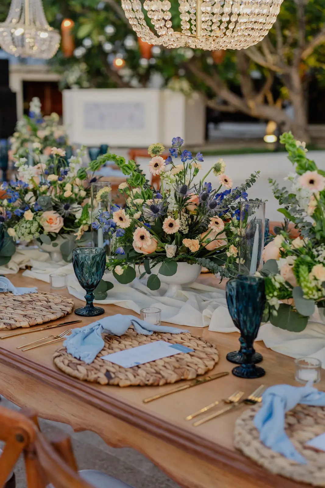 Mesa decorada con flores, cristalería azul y servilletas