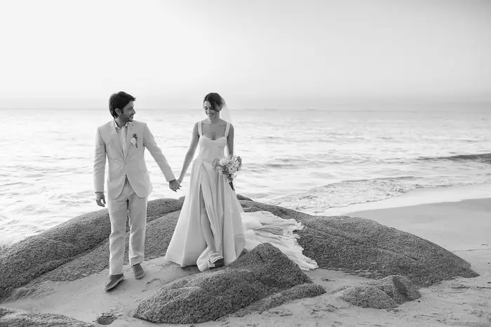 Novios caminando sobre las rocas frente al mar